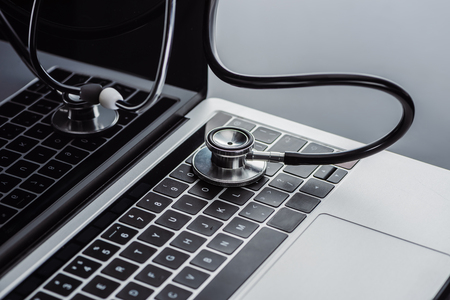 selective focus of stethoscope and laptop with blank screen on grey surfaceの写真素材