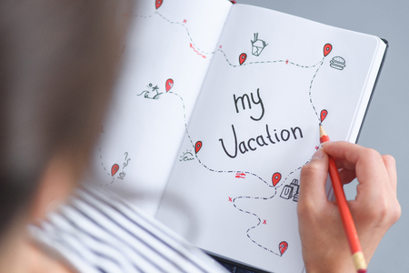 partial view of woman with pencil holding notebook with my vacation inscription, traveling concept