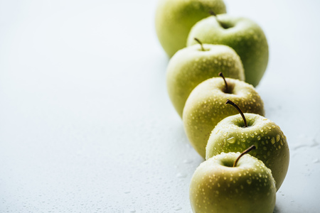 close up view of green apples with water drops on white backgroundの写真素材