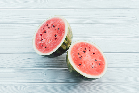 top view of fresh watermelon halves on white wooden surfaceの写真素材