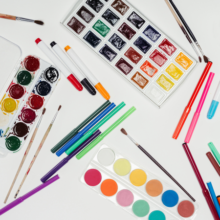 top view of paintbrushes, colorful pants and markers on white tableの写真素材