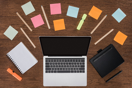top view of workplace with arranged textbooks, post it and laptop with blank screen