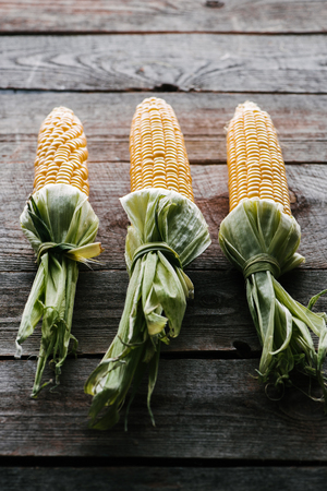 close up view of fresh raw corn cobs arranged on wooden surfaceの写真素材