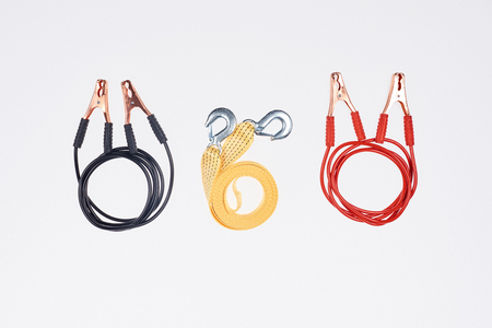 flat lay with arranged car tow rope and jump start cables isolated on white