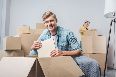 beautiful young couple unpacking boxes while moving into new home