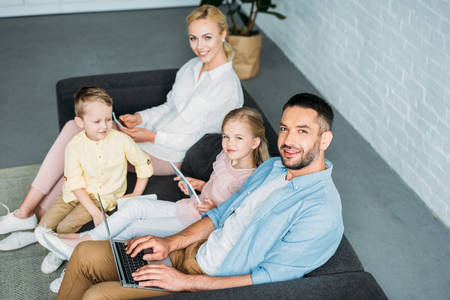 high angle view of happy family using digital devices and smiling at cameraの写真素材