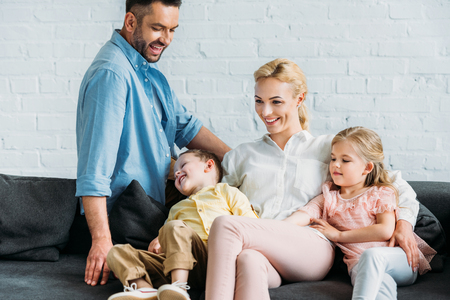 happy family with two kids having fun while sitting on sofa at homeの写真素材