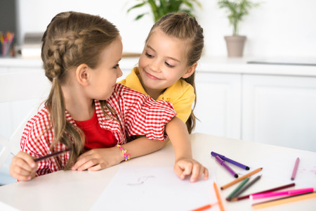 portrait of cute little children at table with papers and pencils for drawing at homeの写真素材
