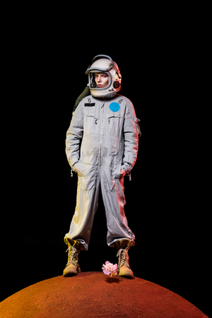 astronaut in spacesuit and helmet standing on peony on planetの写真素材
