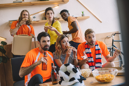 multicultural friends with pizza and beer watching soccer match at home