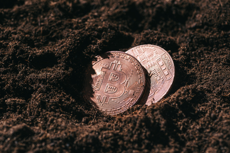 close up view of bronze bitcoins in groundの写真素材