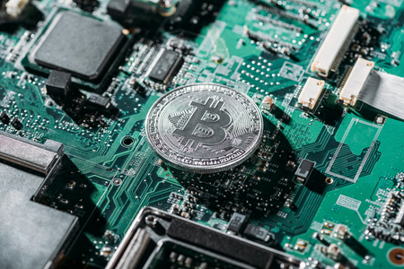 close up view of silver bitcoin on computer motherboardの写真素材
