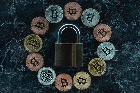 top view of arranged lock and various bitcoins on dark marble surface