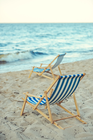 selective focus of wooden beach chairs on sandy beach with sea on backgroundの写真素材