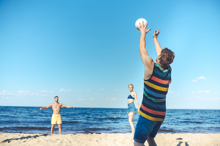 young friends playing volleyball together on sandy beachの写真素材