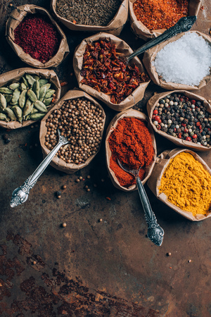 top view of colorful spices in paper bags on brown tabletopの写真素材