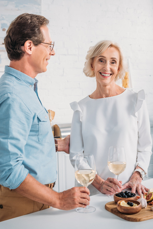 happy elderly couple drinking wine together at homeの写真素材
