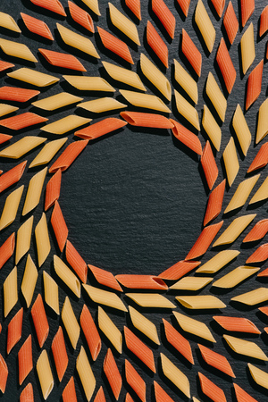 top view of circle frame made of pasta on black surface