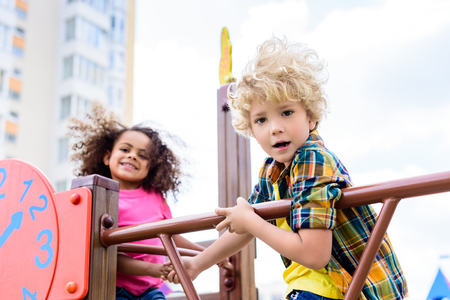 selective focus of two multiethnic little kids having fun at playgroundの写真素材