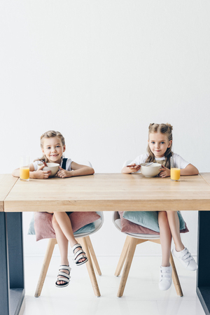 schoolgirls eating cereals for breakfast together on whiteの写真素材