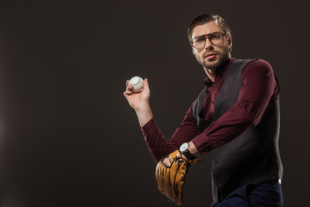 serious businessman in eyeglasses playing baseball isolated on blackの写真素材