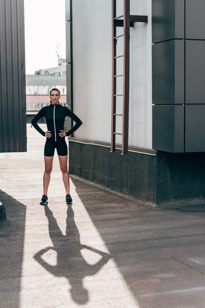 athletic girl posing in thermal clothes on roof in cityの写真素材