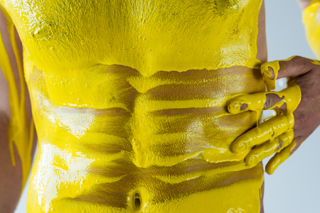 Cropped view of male torso in yellow liquid isolated on white backgroundの写真素材
