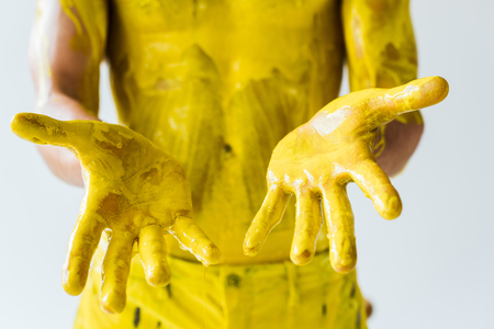 Cropped view of male hands and body in yellow paint isolated on white backgroundの写真素材