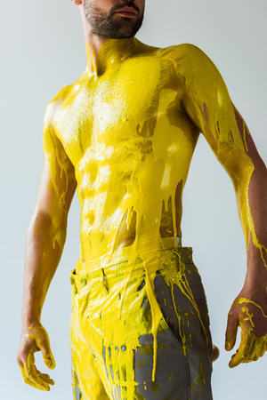 Muscular male body covered with yellow paint isolated on white backgroundの写真素材