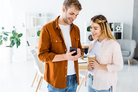 multicultural colleagues looking at smartphone in start up officeの写真素材