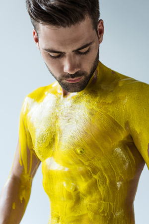 Man looking at his body painted yellow isolated on white backgroundの写真素材