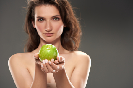 naked girl with fresh green apple, isolated on greyの写真素材