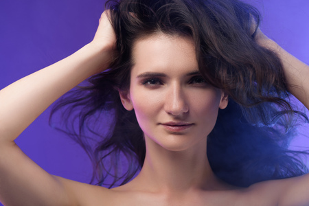 portrait of young beautiful brunette woman on purpleの写真素材
