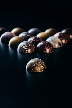 closeup view of pile of chocolate candies on black backgroundの写真素材
