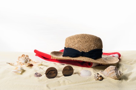Straw hat and sunglasses with seashells in sand isolated on whiteの写真素材