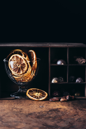 closeup view of bowl with dry orange slices, nuts, chocolate candies and pieces on shelvesの写真素材