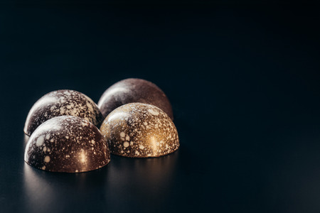 closeup image of chocolate candies with golden splashes on black backgroundの写真素材