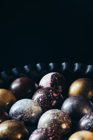 closeup view of pile of different chocolate candies in bowl on black backgroundの写真素材