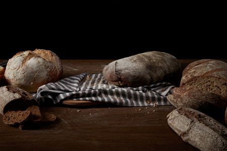 close up view of various types of bread, sackcloth and cutting board on table