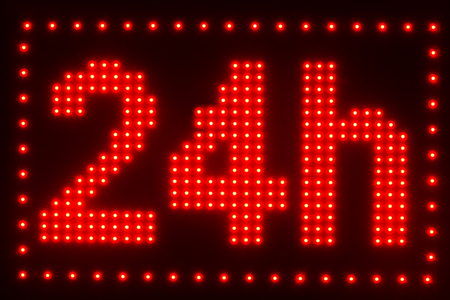 close up view of illuminated twenty four hour sign on dark backgroundの写真素材