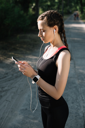 attractive sportswoman with earphones, smart watch and smartphoneの写真素材