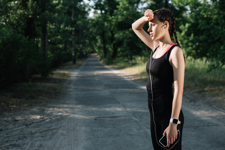 beautiful tired sportswoman listening music with earphones and smartphoneの写真素材