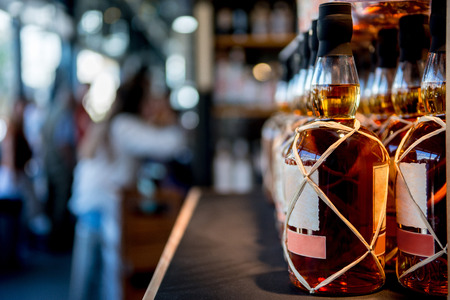 selective focus of whiskey bottles placed in rows on shelf in storeの写真素材