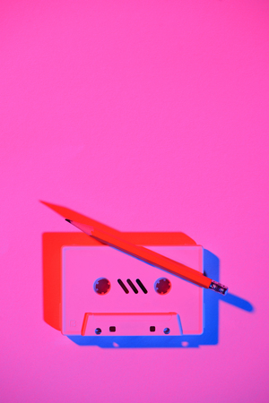 toned pink picture of retro audio cassette and pencil on tabletopの写真素材