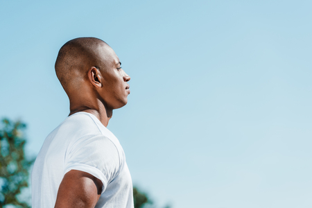 side view of confident african american soldier in white shirt against blue skyの写真素材