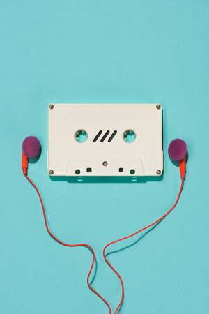 flat lay with white retro audio cassette and earphones isolated on blueの写真素材