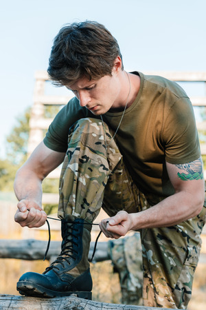 portrait of soldier in military uniform tying shoelacesの写真素材