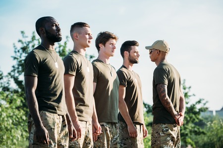side view of african american tactical instructor in sunglasses and young multiethnic soldiers on rangeの写真素材
