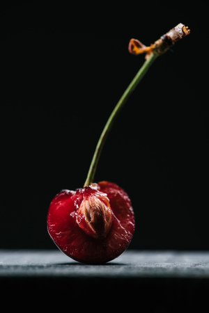 close-up view of half of fresh ripe cherry on blackの写真素材