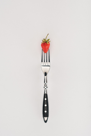 Raw strawberry on a fork isolated on white backgroundの写真素材